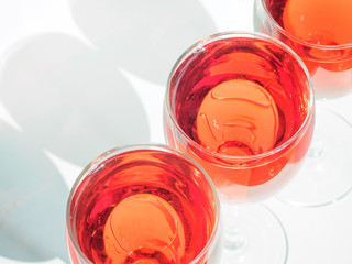 Three wineglass with pink wine on white background