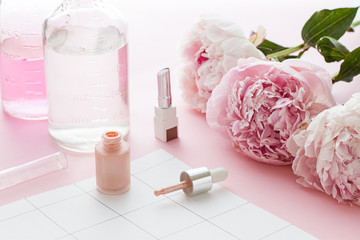 Cosmetics bottles on the pink background with flowers.Close up