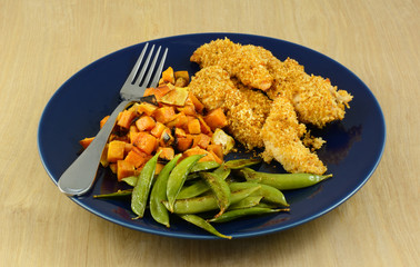 Dinner plate of roasted yams, beans and baked chicken tenderloins with crispy bread crumb crust