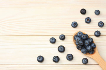blueberries in wooden spoon on light wooden table background. top view with copy space