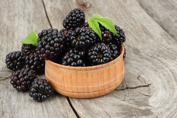blackberries in wooden bowl on old wooden table background