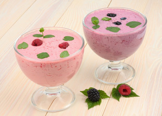 Healthy raspberries and blackberries yogurt with fresh berries on light wooden background