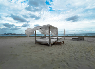 Big sun bed alcove on the windy sand shore, fluttering in the wind, waving, raising white curtains,...