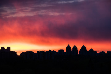 colorful fiery sky at sundown with cirrus clouds above the city skyline