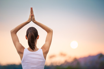 Woman meditating on the beach at sunset.