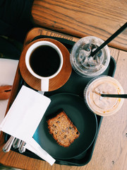 Cold iced and hot coffee in plastic cup with grape cake at coffee shop.