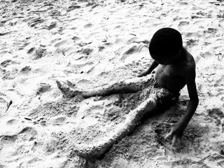 boy sitting in sand on a beach in the caribbean