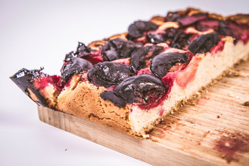 Plum pie on a wooden chopping board on a white background