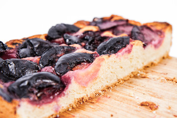 Plum pie on a wooden chopping board on a white background