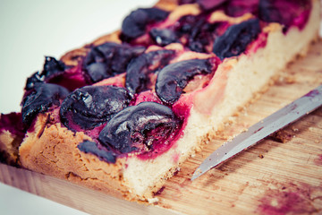 Plum pie on a wooden chopping board on a white background