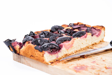 Plum pie on a wooden chopping board on a white background