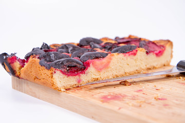 Plum pie on a wooden chopping board on a white background