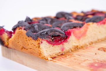 Plum pie on a wooden chopping board on a white background