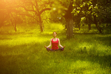 Yoga practicing. Female sitting and mediating in Easy pose with crossed legs. Yoga exercise Sukhasana. Toned image.