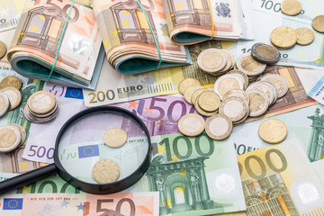 magnifying glass and euro banknotes, euro coin