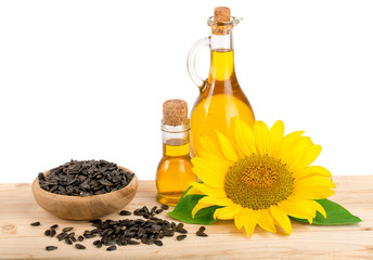 Sunflower oil, seeds and flower on wooden table with white background