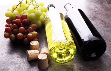 Bottle of white and red wine, grape and corks on wooden table