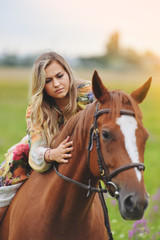 Obraz premium Young woman sits on a horse in a summer meadow