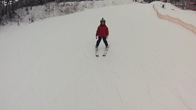 A little girl with gopro on her helmet taking her first ski lesson