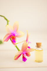 Fototapeta na wymiar Essence of orchid flowers on table in beautiful glass jar