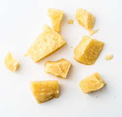 Parmesan cheese pieces on white background. Italian cheese slices. Top view.