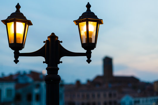 Old beautiful street lamp shines at evening