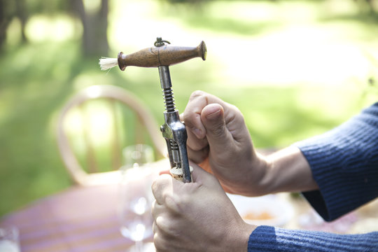 Hands opening wine bottle with wine opener
