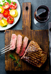 Sliced grilled medium rare beef steak served on wooden board Barbecue, bbq meat beef tenderloin. Top view, slate background