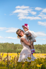Funny baby girl in white dress is playing with mother  in the garden at christening