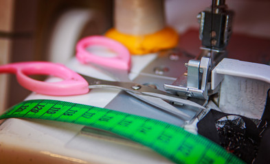 Tailor scissors closeup, measuring tape and sewing machine