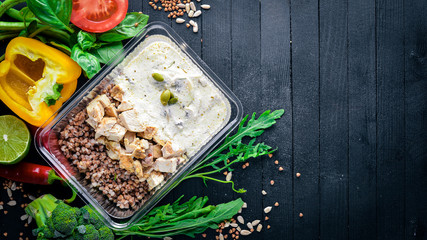 Buckwheat with meat and fresh vegetables. Healthy Diet Food. Lunch Boxing. On a black wooden background. Top view. Free space for text.