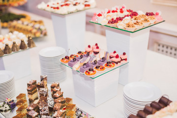 Delicious and tasty dessert table with cupcakes shots at reception closeup