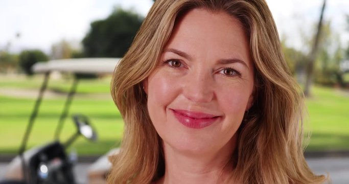 Close up of middle aged Caucasian woman on golf course smiling at camera