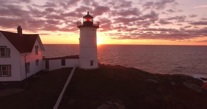 Lighthouse and American Flag with Warm Sunrise in Traveling Shot - Aerial Footage of Cape Neddick Lighthouse, Maine, USA