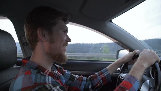 Young smiling man driving car, view from front passenger seat