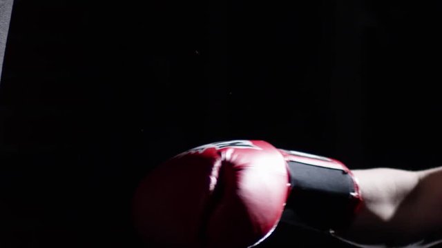 Fighter Practicing Some Kicks With Punching Bag - A Man With A Tattoo Boxing On dark Background. Kick, punching bag on dark background. Black punching bag weighs at the gym