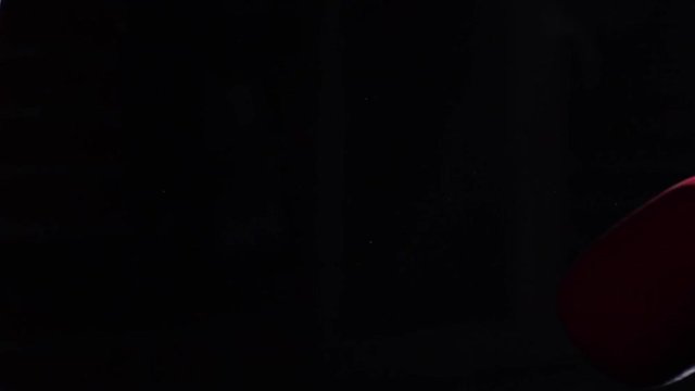 Fighter Practicing Some Kicks With Punching Bag - A Man With A Tattoo Boxing On dark Background. Kick, punching bag on dark background. Black punching bag weighs at the gym