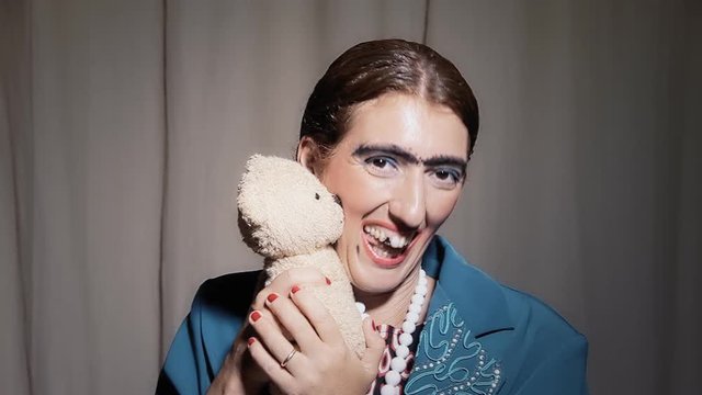 A funny ugly woman cuddling a cute teddy bear. Comedy shot.
