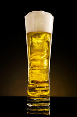 Still life - Glass of blonde beer in dark background.