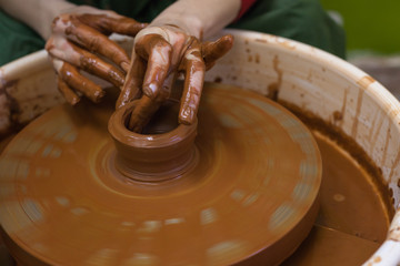Female hands work with clay. Work in the pottery workshop. The Potter's wheel in operation. Process in the pottery workshop.