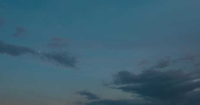 Time lapse clip of evening fluffy curly rolling clouds with moon
