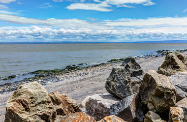Fototapeta na wymiar Closeup of rocks and Saint Lawrence river in Saint-Irenee, Quebec, Canada in Charlevoix region with beach