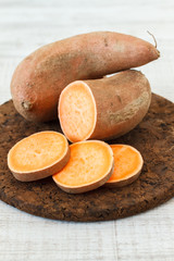 Raw sweet potatoes on wooden background
