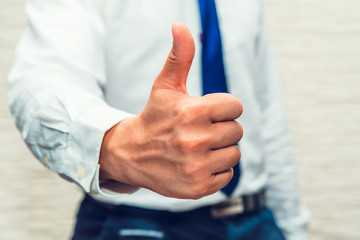 Male wearing white business shirt and blue tie show thumb up using his hand. Thats ok, good, well done, agree, accepted. I like to see this, i am happy to see result of your job.