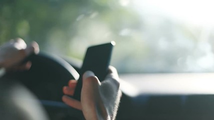 Close-up male person hand using utilizing holding cellphone smartphone phone driving car driver blurred street sunny dangerous busy man hands steering wheel touchscreen typing traffic device gadget