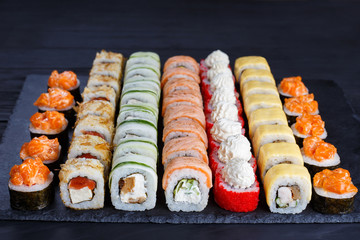 Appetizing maki sushi set, served on black stone slate. Restaurant menu, Japanese food art.