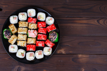 Colorful set of japanese sushi maki rolls with salmon, tuna and avocado served on round plate, flat lay.