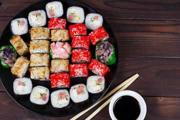 Tasty great set of japanese sushi maki rolls served on round plate, with soy sauce and chopsticks, flat lay. Food art, traditional seafood, restaurant menu photo