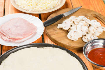 Pizza dough with pizza ingredients mushrooms sliced ham cheese