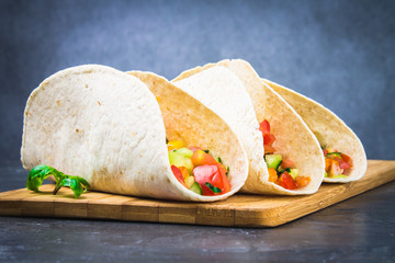 Traditional Mexican tacos with meat and vegetables on wooden background
